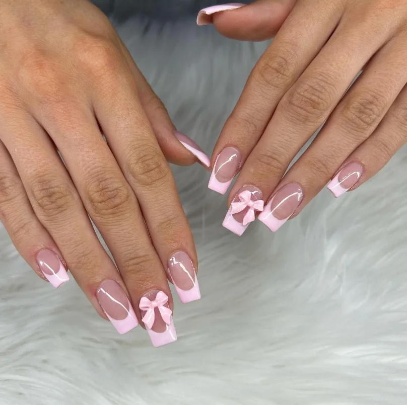 Cute 3D bow acrylic nails with soft pink polish and raised bow details.