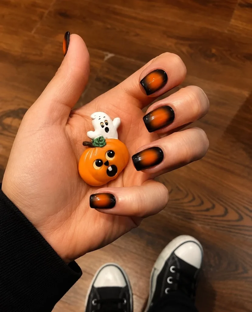 Black and orange aura Halloween nails with a soft glowing gradient finish.