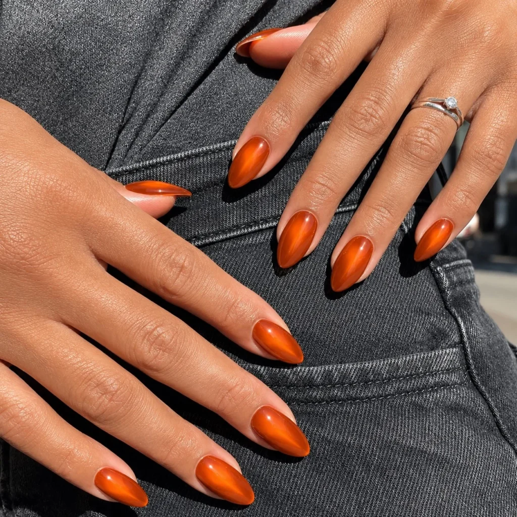 Burnt orange aura nails with soft blended glow and glossy autumn manicure.