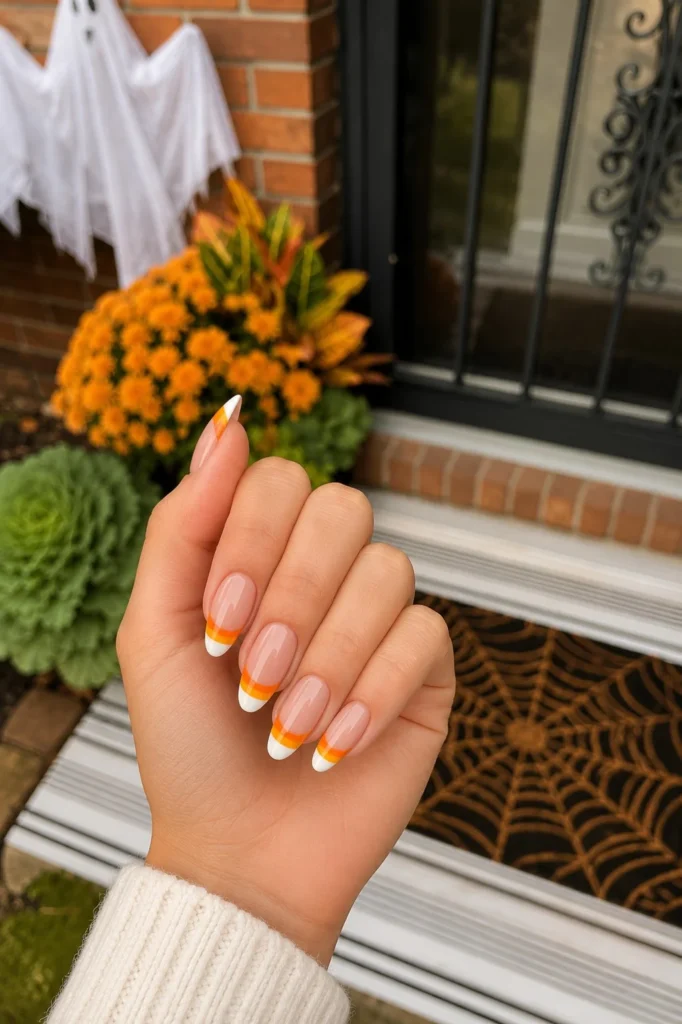 Candy corn French tip Halloween nails with yellow, orange, and white tips.