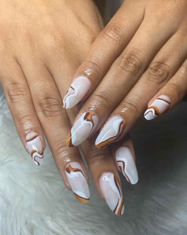 Caramel swirl nail design with warm brown marble details and glossy finish.