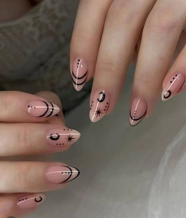 Celestial moon and star acrylic nails with gold celestial accents on nude base.