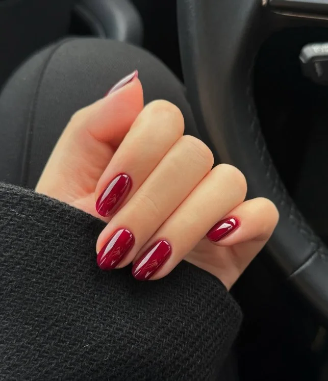 Classic cherry red nails on pale skin with a shiny finish