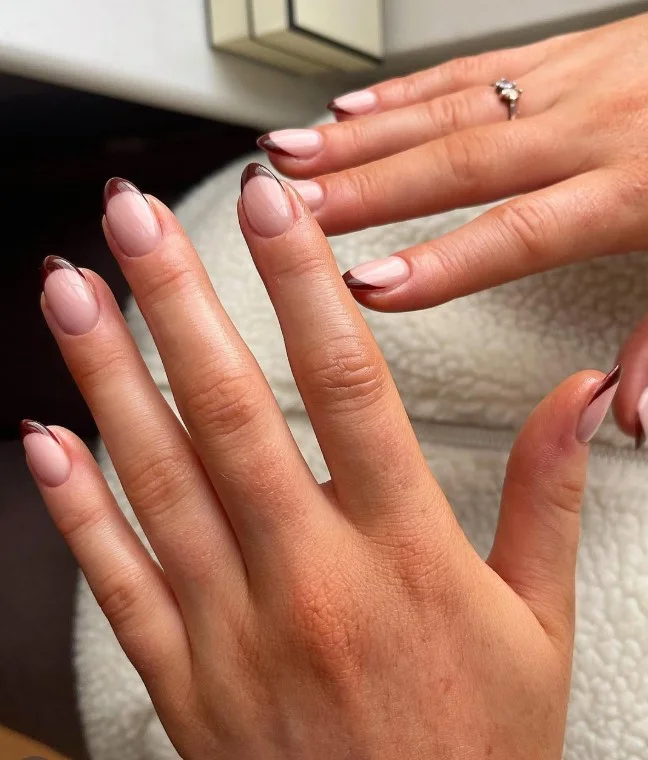 Chocolate brown French tip nails on a nude base with elegant fall nail design.