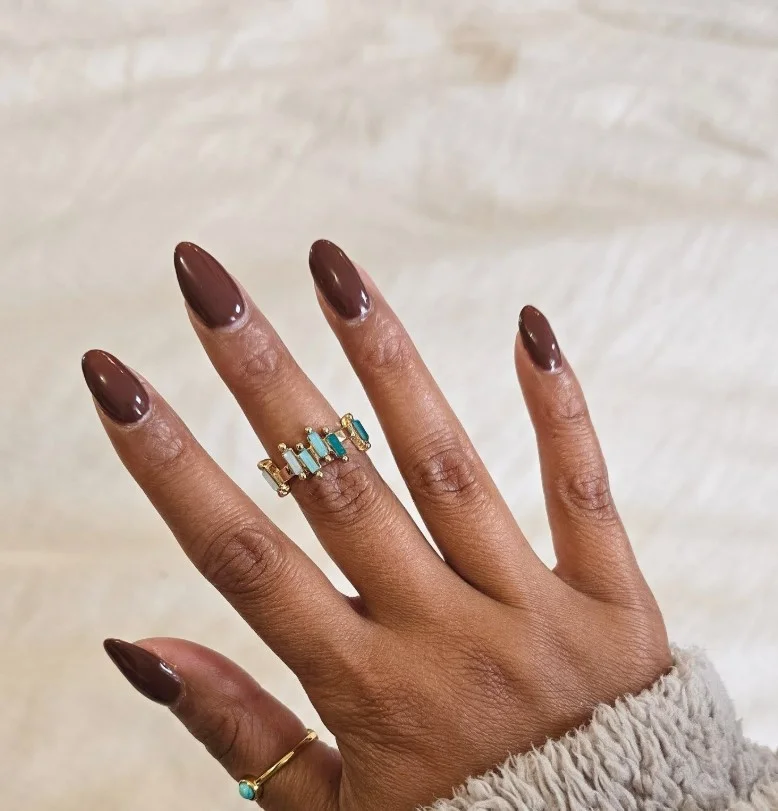 Chocolate brown manicure on tan skin with elegant oval nails.