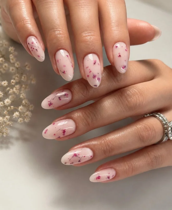 Clear acrylic nails with encapsulated dried flowers inside transparent glossy manicure.
