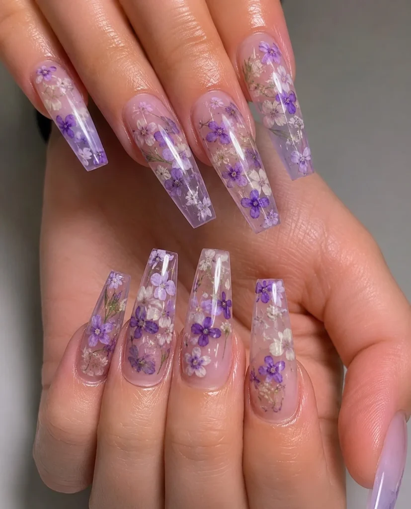 Clear lavender nails with encapsulated dried flowers inside glossy transparent nail design.
