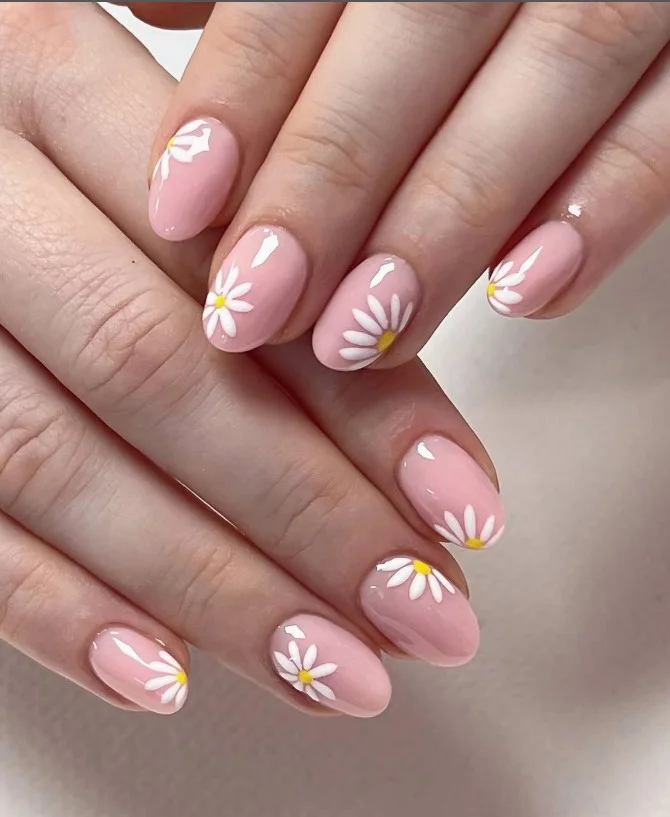 Cute short nails with dainty white daisy flowers and soft pink glossy polish.