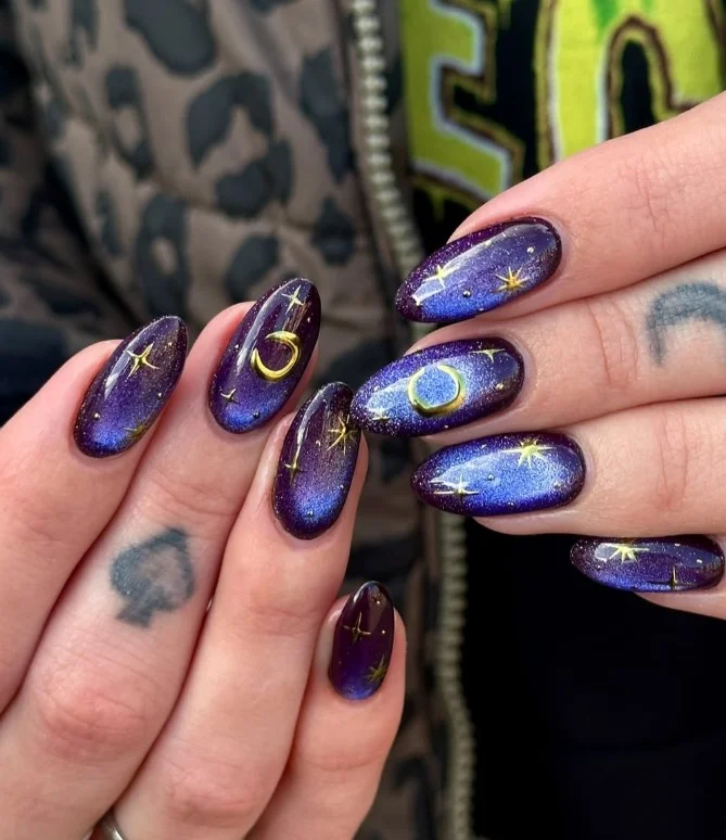Dark purple galaxy nails with shimmering celestial nail art and glitter accents.