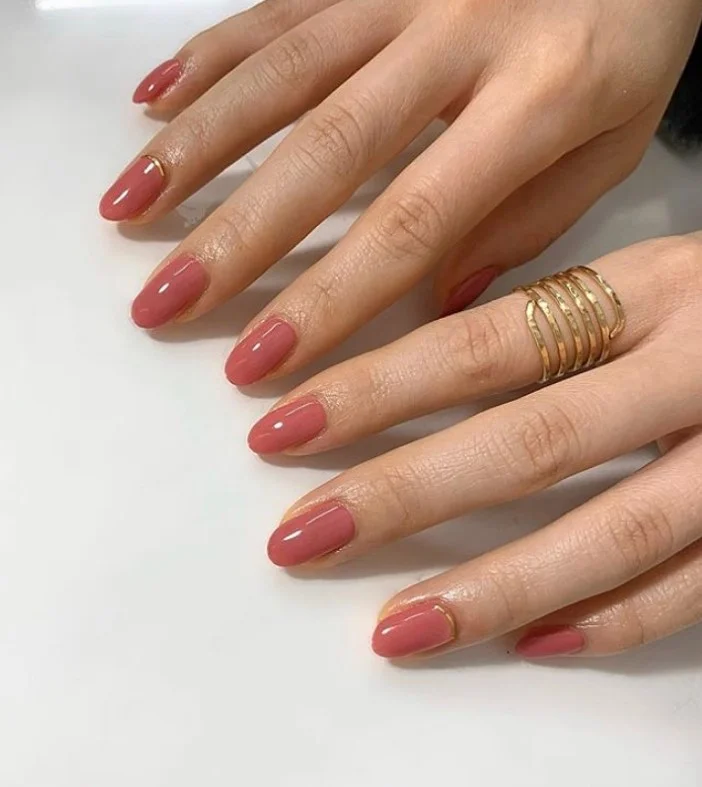 Dusty rose nail color on tan skin with a natural glossy look.