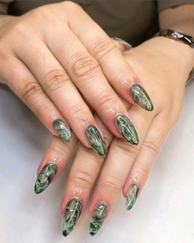 Forest green marble nails with elegant white stone-inspired swirl details.