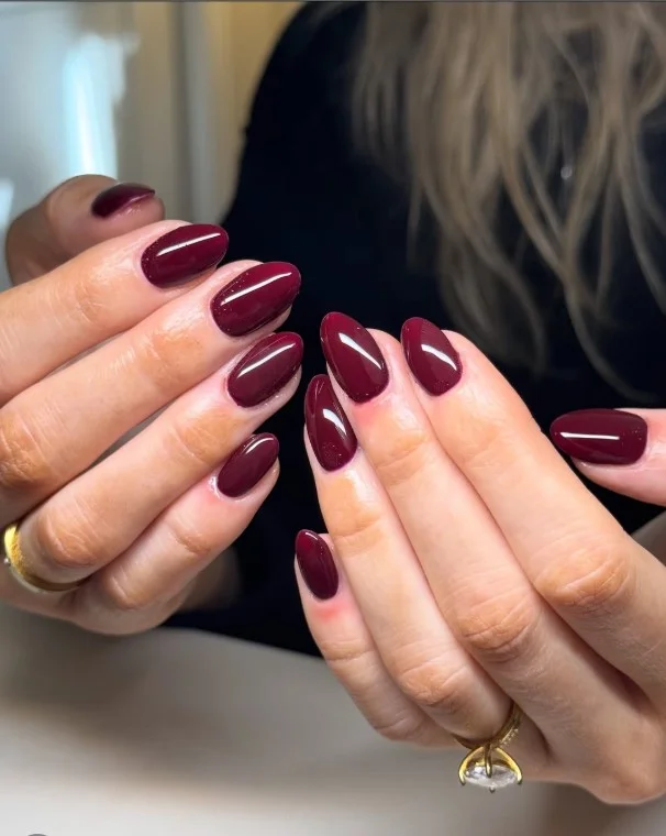 Glossy burgundy almond nails with rich deep red autumn manicure and high-shine finish.