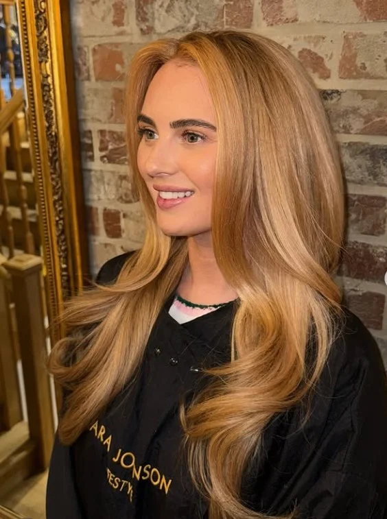 Golden strawberry blonde hair with soft curls and natural shine.