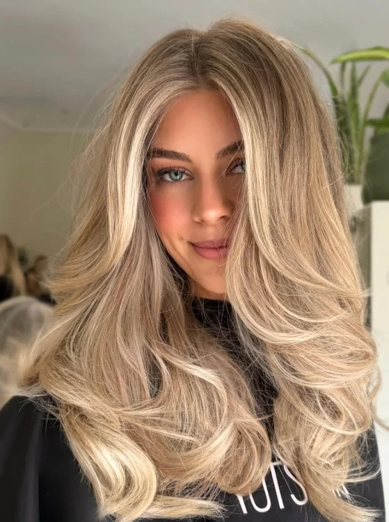 Icy beige blonde balayage with loose waves for red skin tone.
