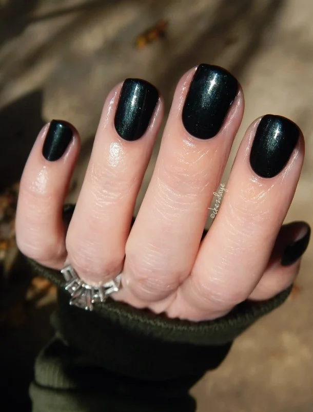 Jet black nails on pale skin with a bold glossy manicure