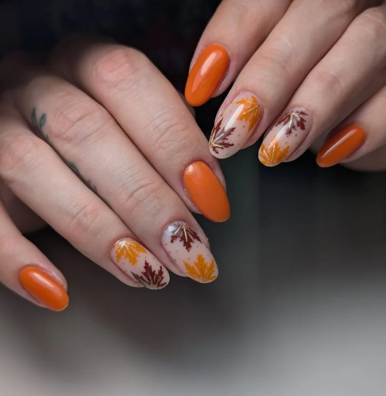 Maple leaf nail art featuring detailed autumn leaves on nude almond nails.