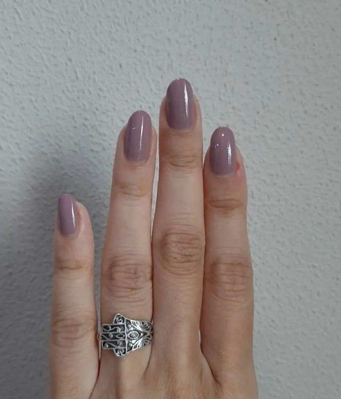 Mauve taupe nail color on pale skin with a modern neutral finish