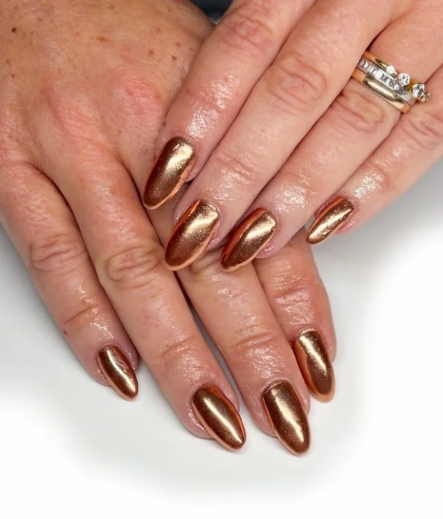 Metallic bronze manicure on tan skin with a radiant glossy look.