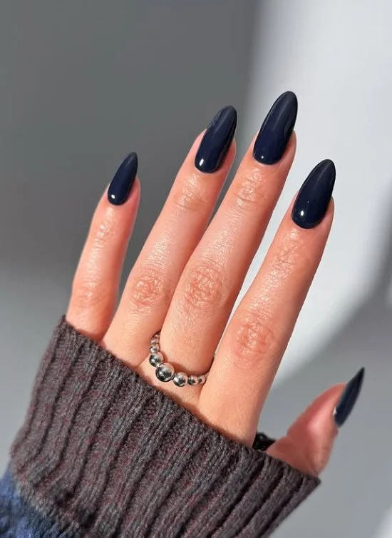 Navy blue manicure on tan skin with glossy square nails.