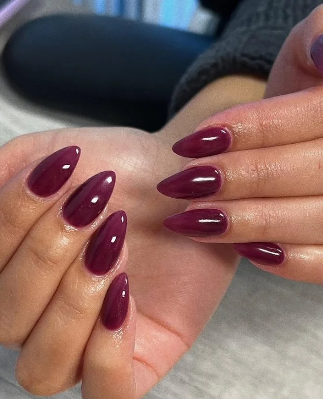 Plum nail polish on tan skin with an elegant glossy finish.