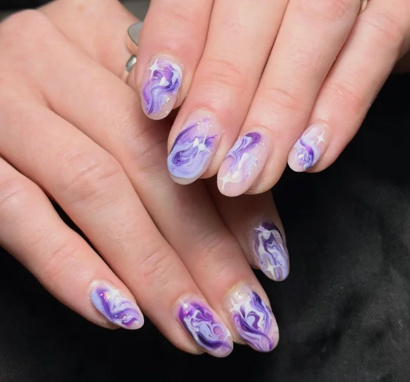 Purple marble swirl nail art featuring lilac and white stone-inspired design.