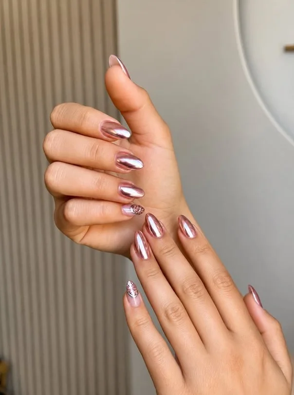 Rose gold shimmer nails on tan skin for a glamorous manicure.