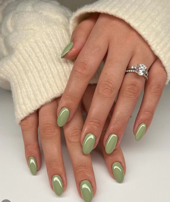 Sage green nail polish on tan skin with a modern matte finish.