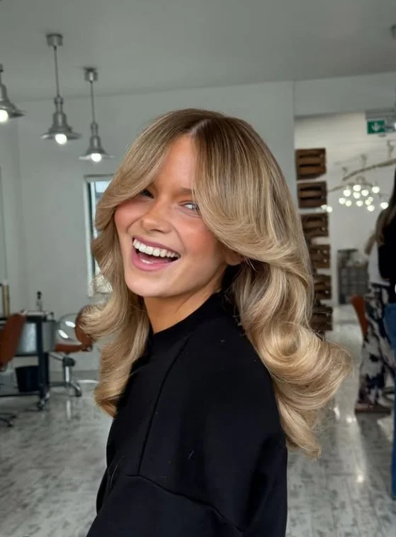 Sandy bronde hairstyle with natural waves reducing the appearance of redness.