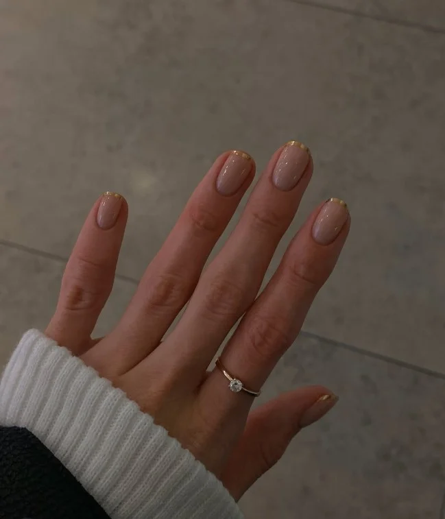 Short nude nails with gold foil details on glossy nude base.