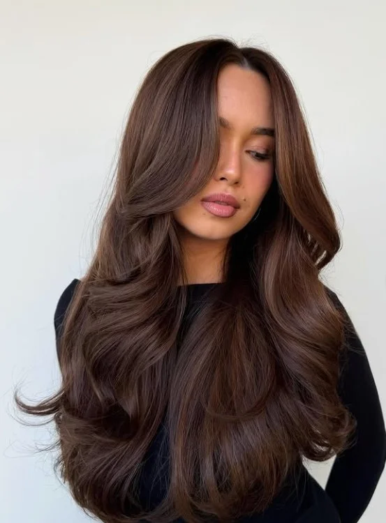 Smoky brunette balayage with soft curls for balanced facial complexion.