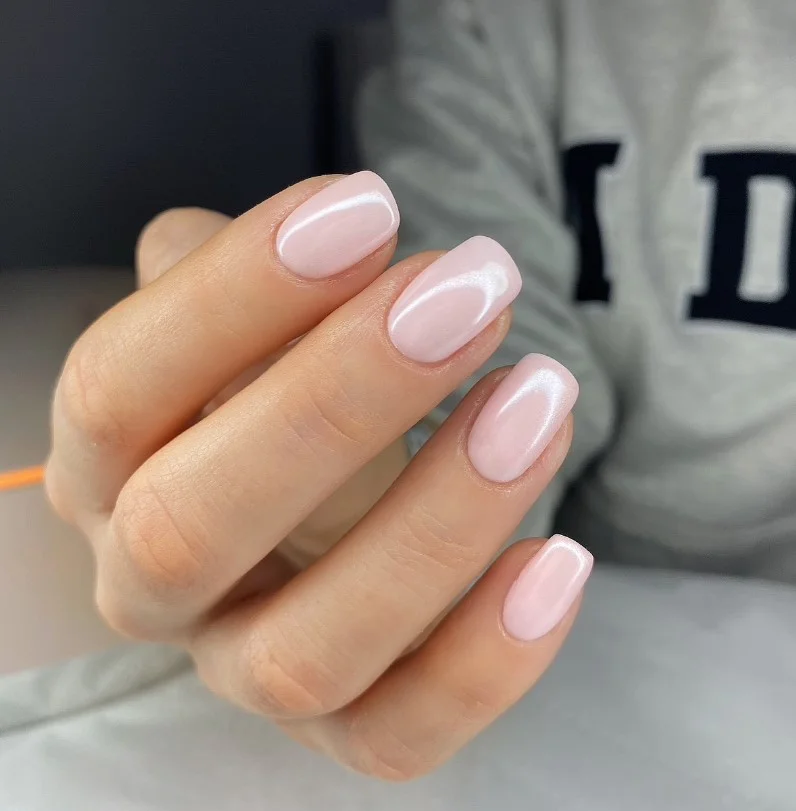 Soft ballet pink nails on pale skin with a glossy natural manicure