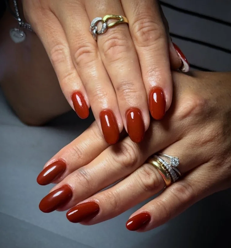 Warm terracotta manicure on short almond nails for tan skin.
