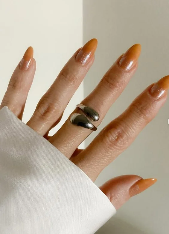 Caramel nude manicure on tan skin with glossy almond-shaped nails.