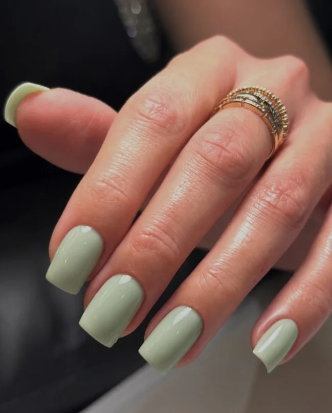 Sage green manicure with a modern glossy finish for pale hands.
