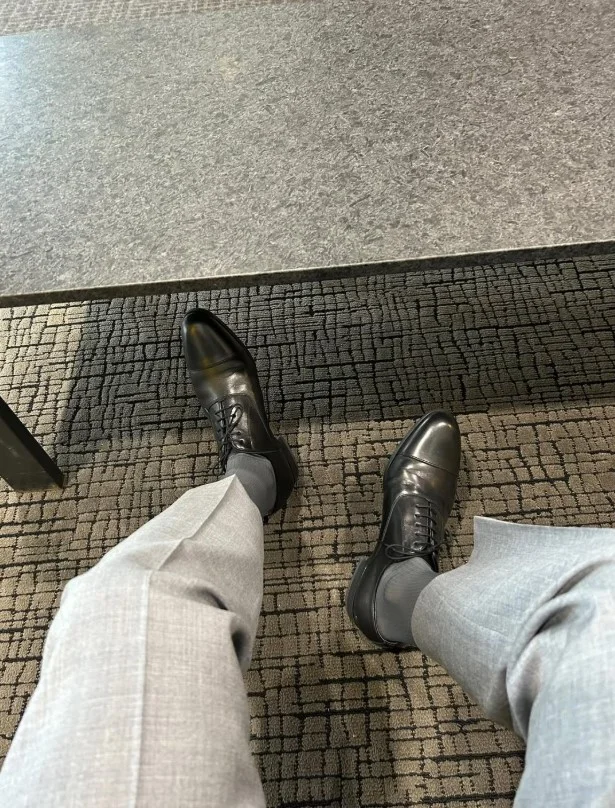 Black leather Oxford shoes paired with charcoal grey dress pants for a formal outfit.