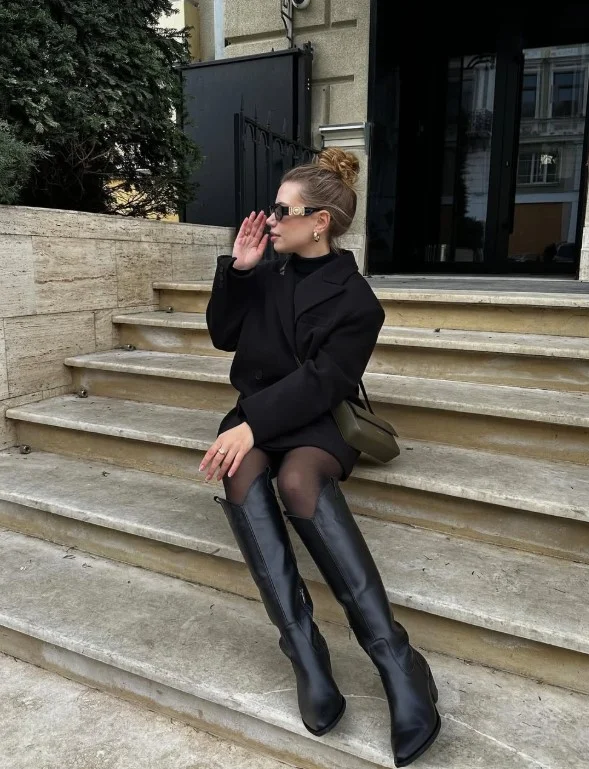 All-black winter outfit with statement coat and thigh-high boots