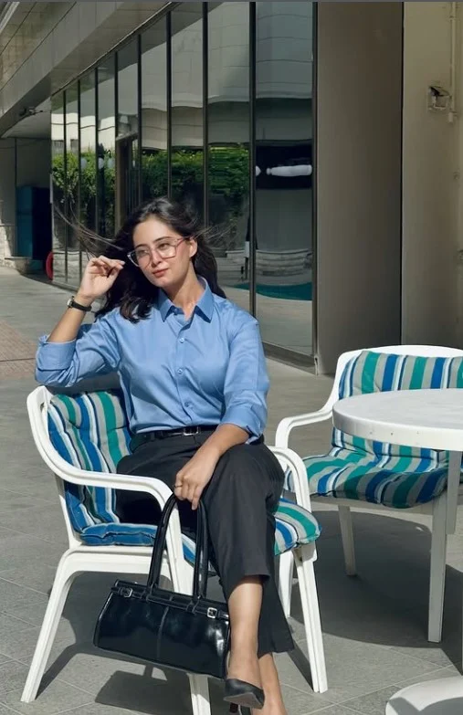 Blue button down shirt tucked into black wide-leg trousers