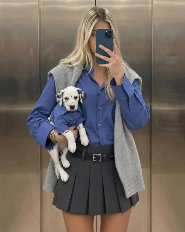 Blue button down shirt tucked into a pleated midi skirt