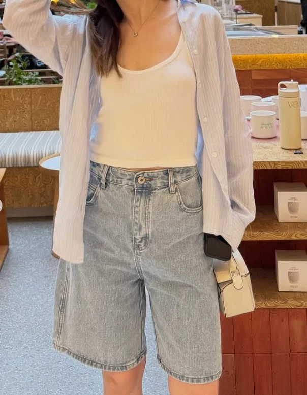 Blue button down shirt worn open over a white tank top