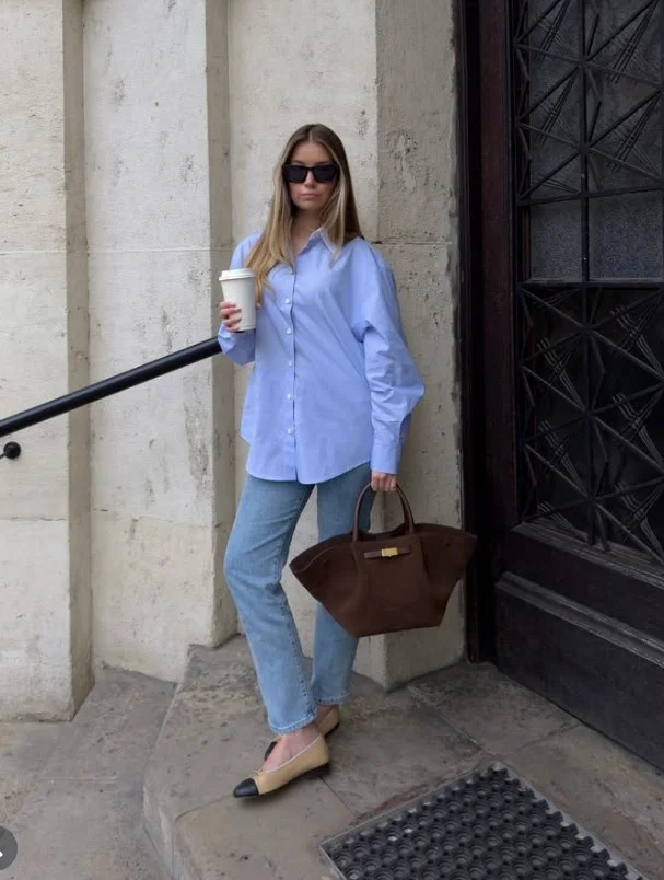 Woman wearing light blue jeans with a darker blue denim shirt and brown shoes