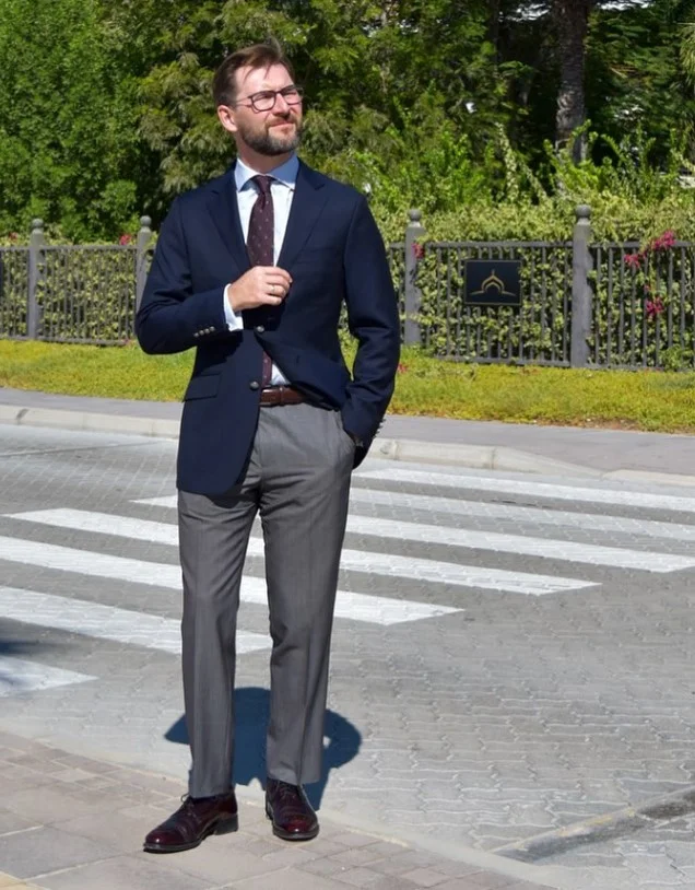 Burgundy leather dress shoes matched with tailored grey trousers and a navy blazer.