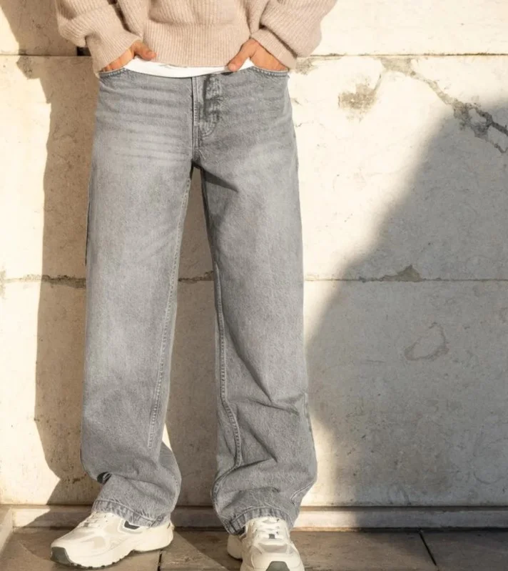 Cream minimalist sneakers paired with grey pants for everyday casual style.