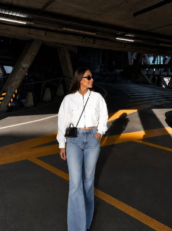 Woman in high waisted jeans with a cropped jacket and simple top