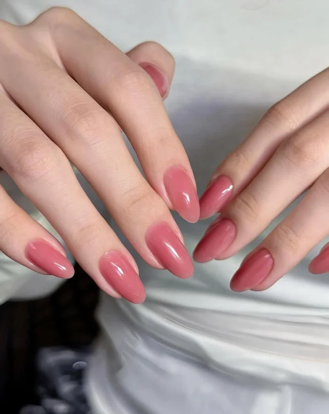 Dusty rose manicure paired with delicate silver rings.