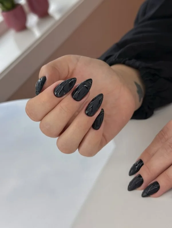Glossy black nails styled on short square-shaped nails.