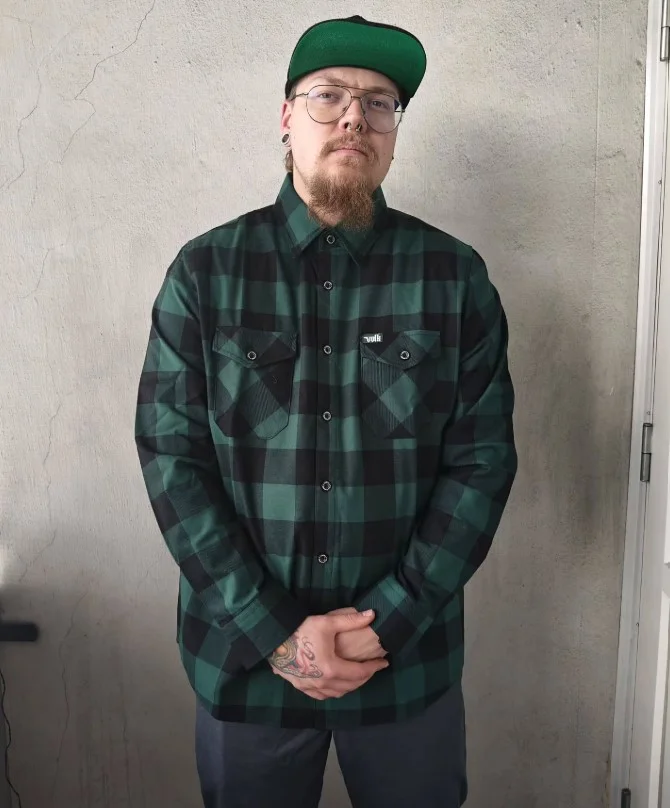 Green flannel shirt paired with gray jeans and casual shoes