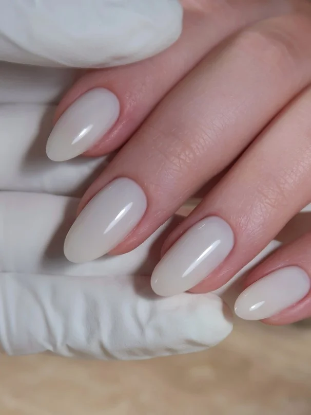 Milky white manicure creating a fresh look on fair skin.
