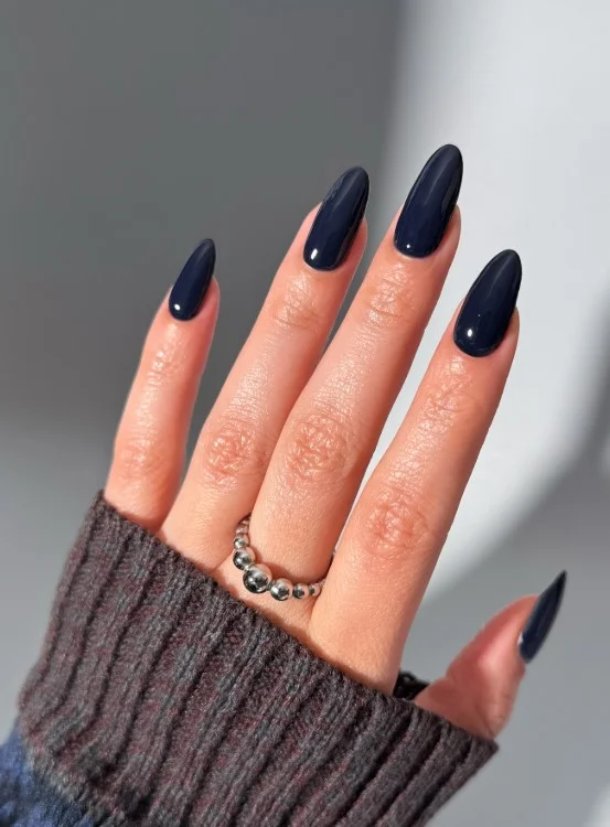 Navy blue manicure creating bold contrast on pale skin.