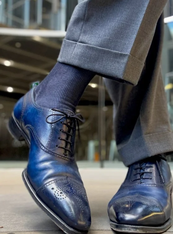 Navy suede loafers paired with medium grey pants for a modern business casual outfit.