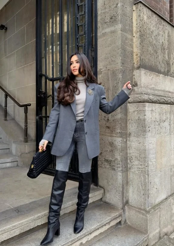 Woman wearing dark high waisted jeans with an oversized blazer and ankle boots